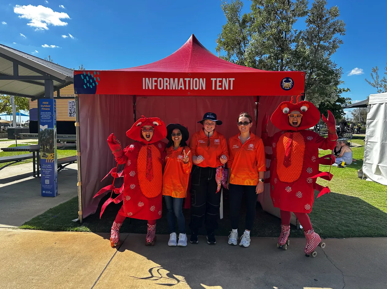 City of Mandurah event volunteers and crab mascots stand in front of an information tent.